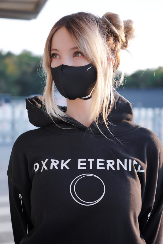 White women wearing a Cyberpunk themed facemask in black and Dxrk Eternity Hoodie